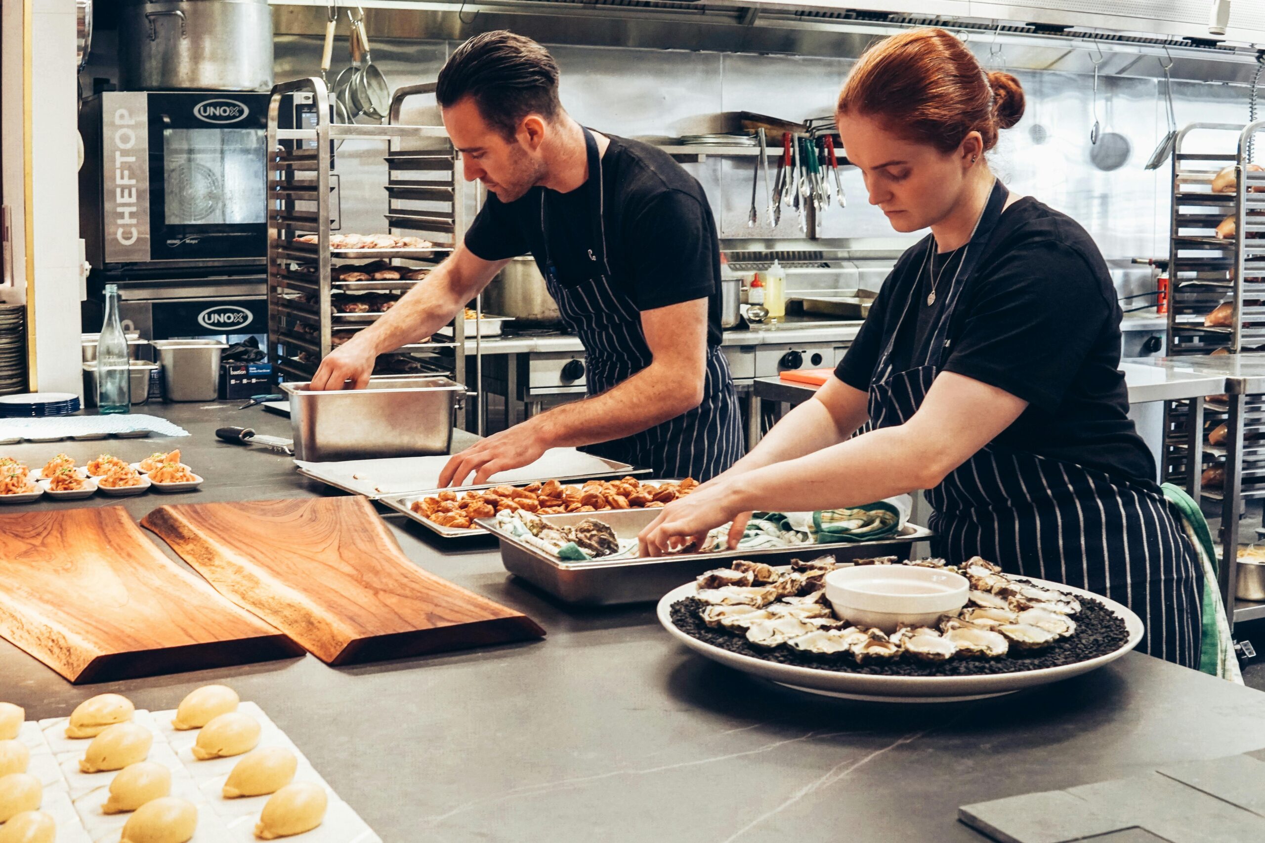 In the kitchen, two persons are making the dishes.
